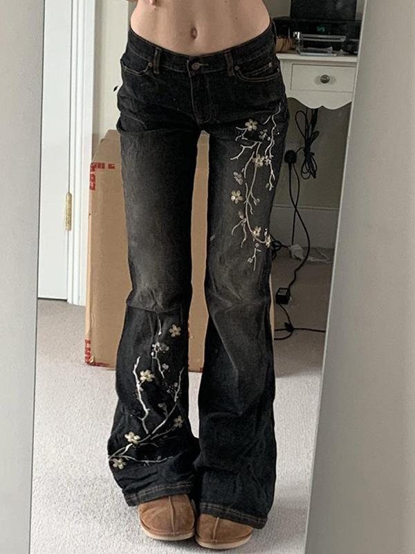 Dark wash wide-leg jeans with white floral embroidery on the legs and brown shoes.