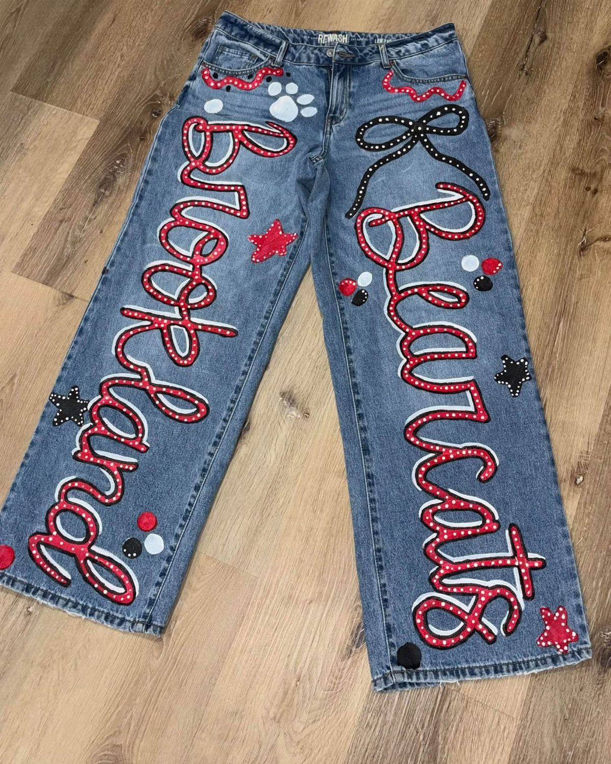 Blue denim jeans with red and white cursive lettering and spirit patches.