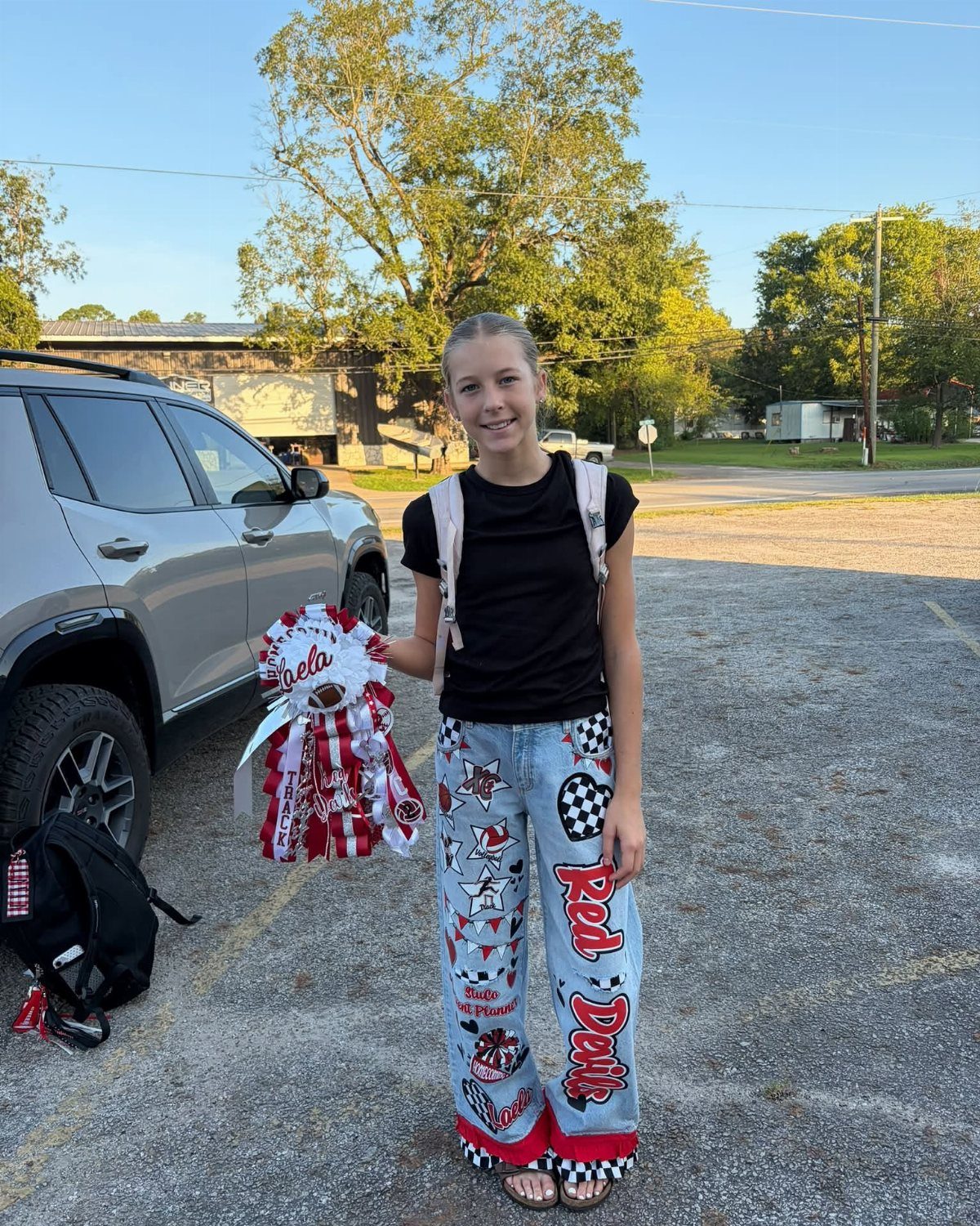 Young woman wearing decorated light wash wide-leg jeans and holding a pom-pom.