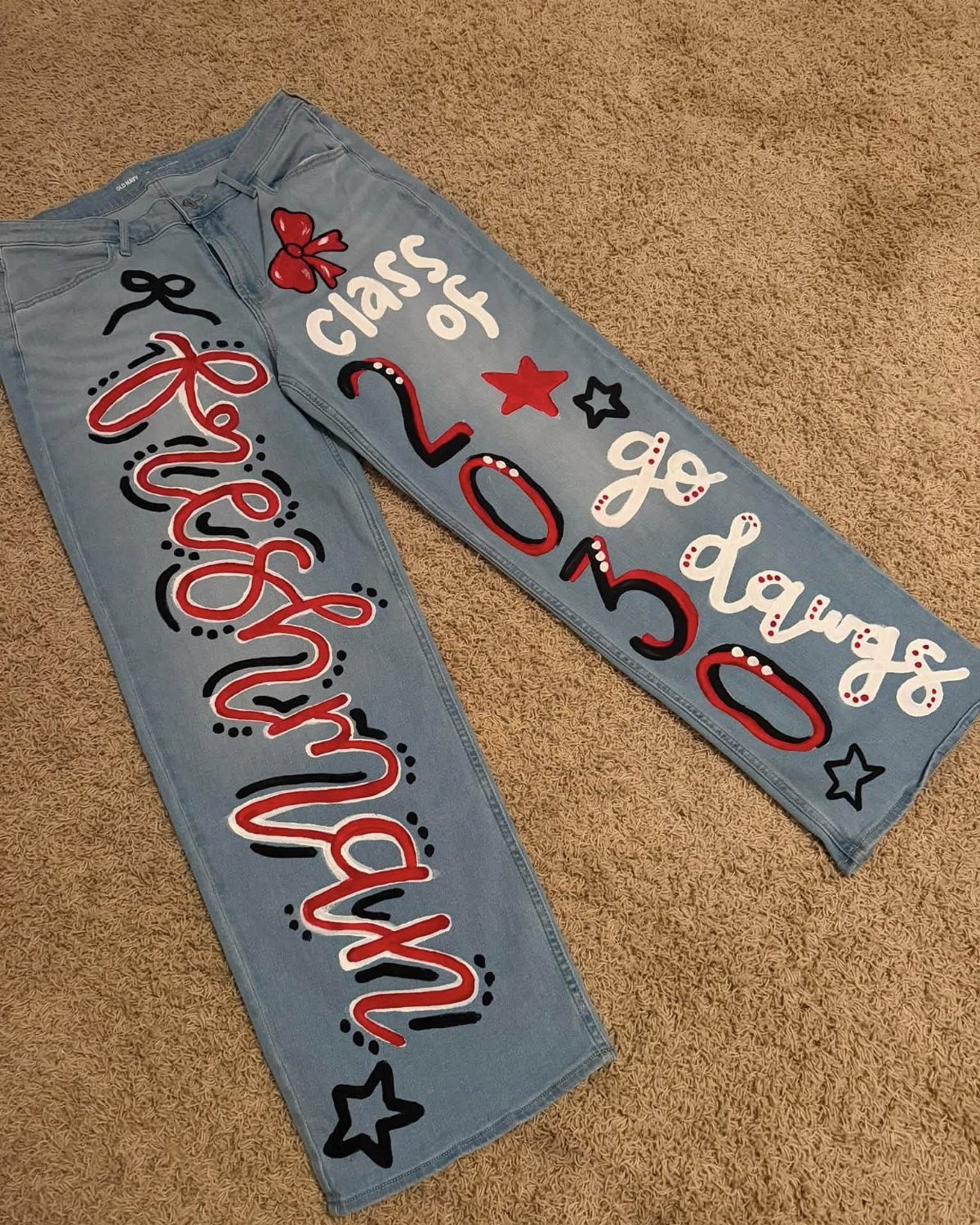 Light blue jeans with hand-painted red and white text and stars on carpet
