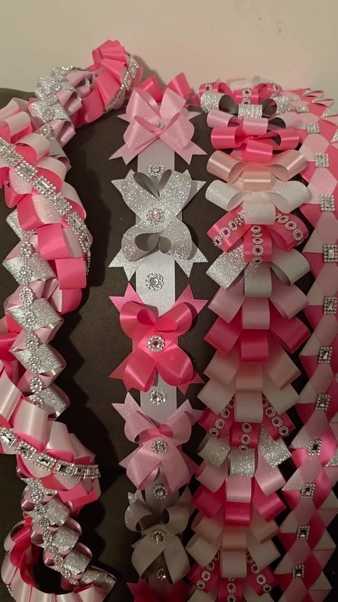 Pink and silver homecoming mum with decorative bows and braided ribbon borders.