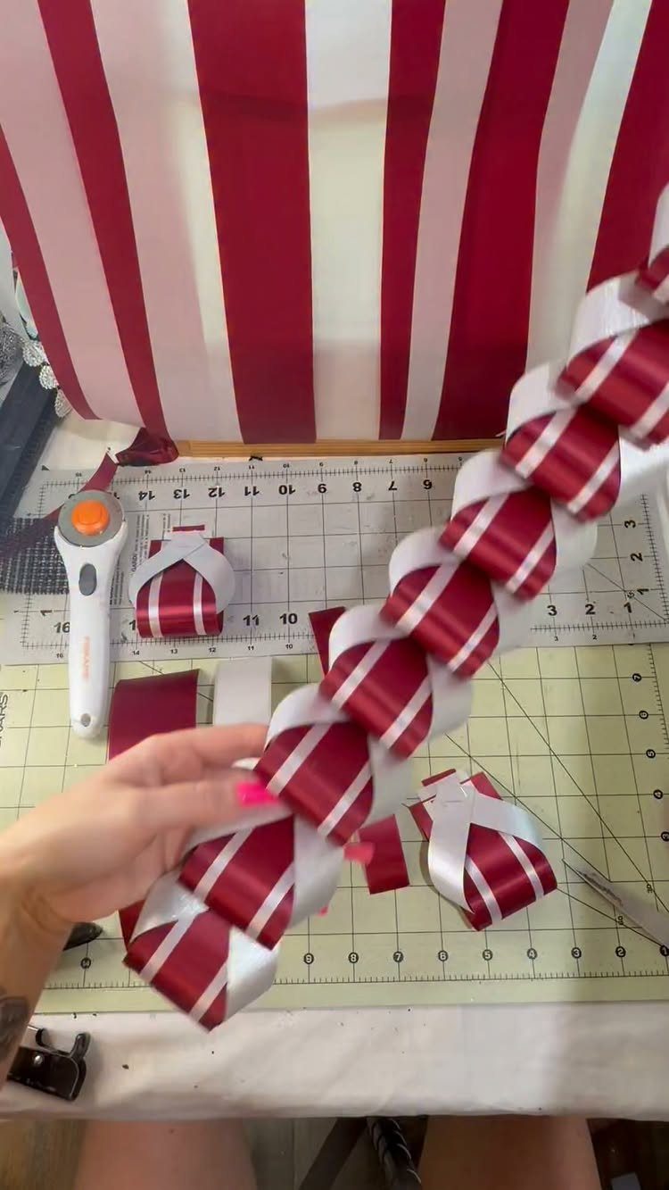 Braided red and white satin ribbons held over a green craft cutting mat.