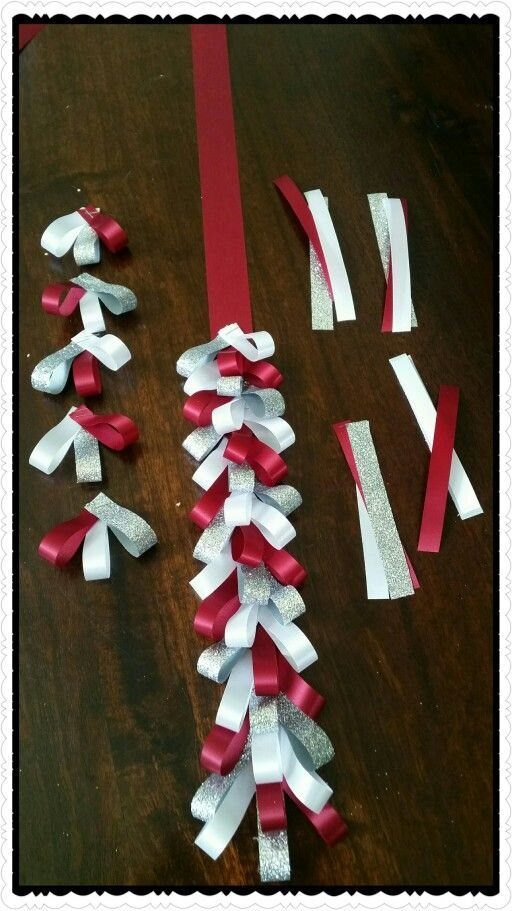 Red, white, and silver glitter ribbons braided into small loops on wood.