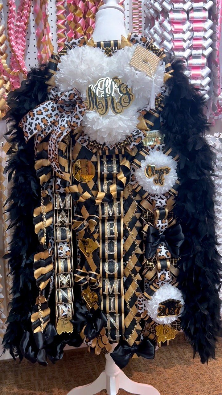 Elaborate black and gold homecoming mum with white pom-poms and black feather boas.
