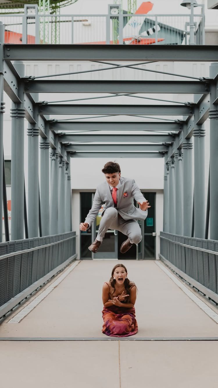 Young man in a suit jumping over a woman in a formal dress.