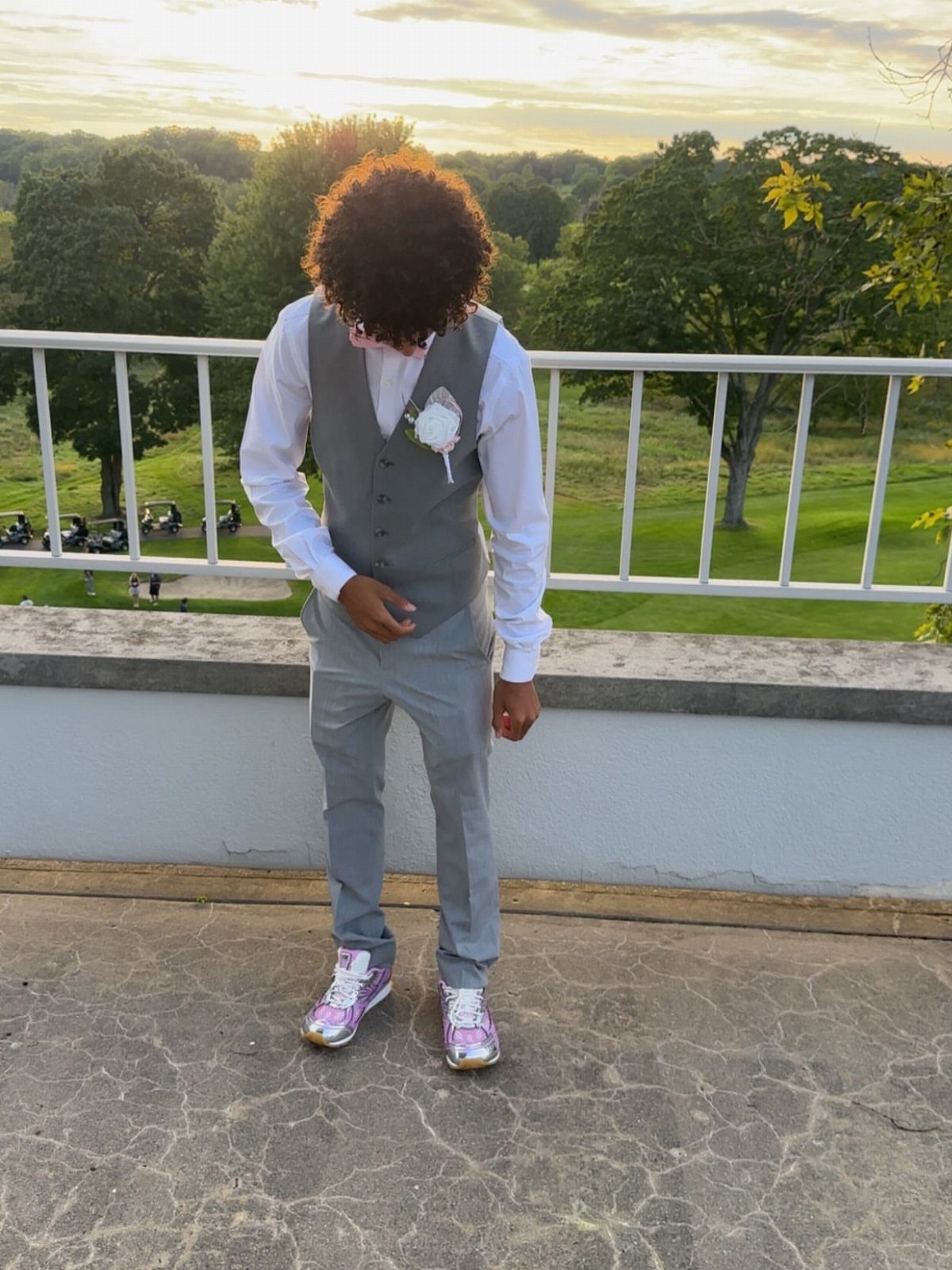 Young man in a grey suit vest and trousers wearing iridescent purple sneakers.