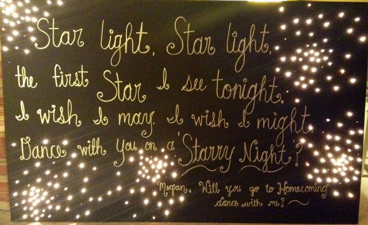 Navy blue poster board with white calligraphy and twinkling warm white fairy lights.