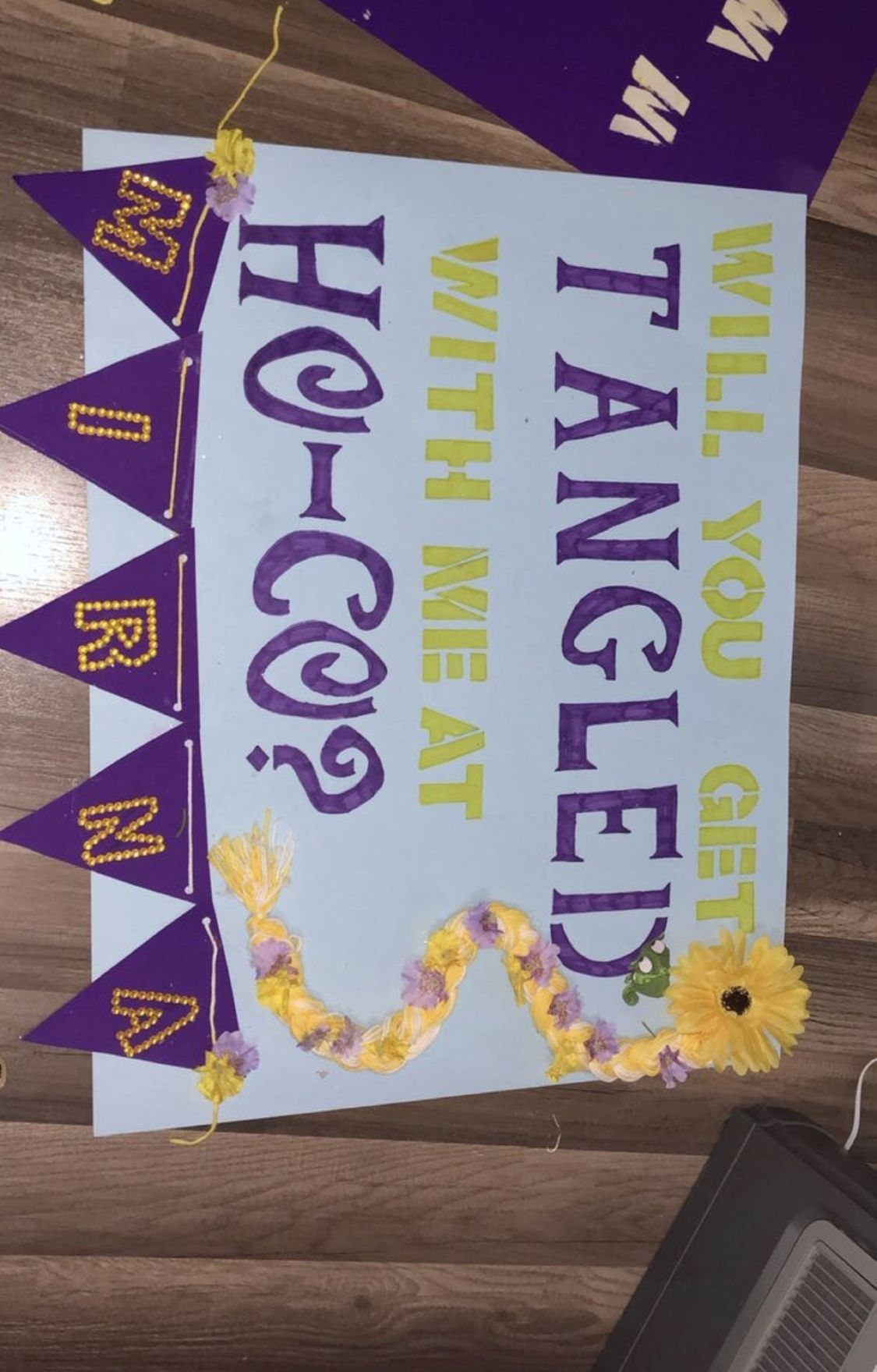 Tangled themed homecoming poster with purple text and yellow floral decorations on white board.