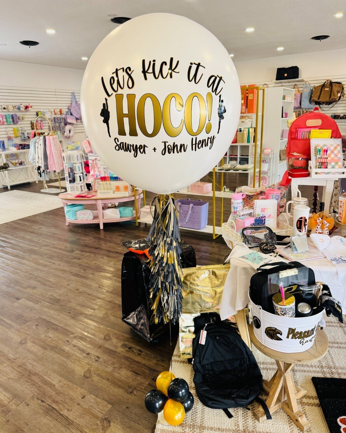 Large white balloon with homecoming proposal text and gold tassels in a store