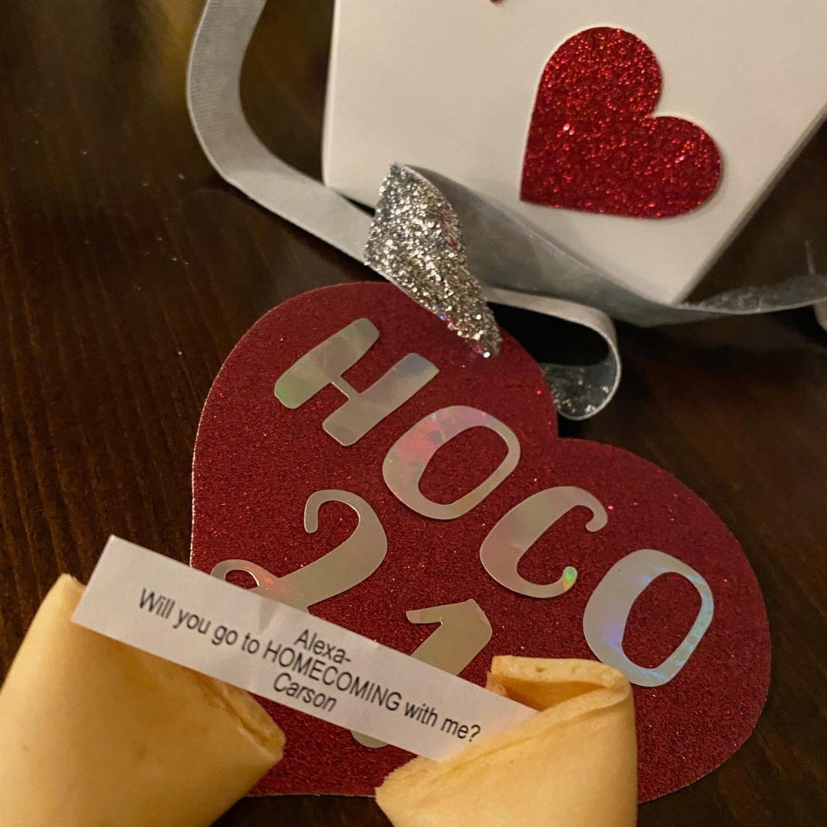 Broken fortune cookies with a homecoming proposal note and a red glittery heart.