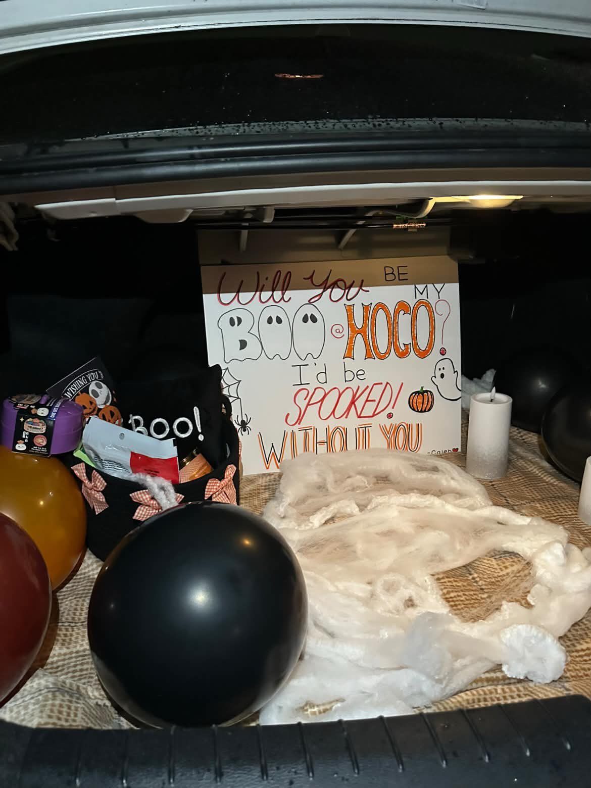 Homecoming proposal sign with ghost theme in a car trunk with balloons