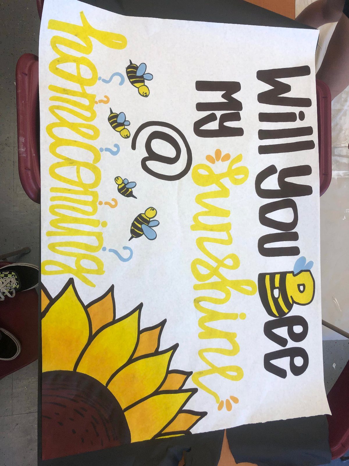 Hand-drawn homecoming proposal sign with bees and a sunflower on white poster board