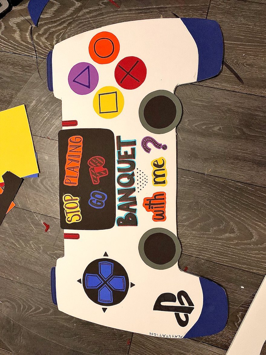 Handmade poster shaped like a video game controller asking someone to a banquet.