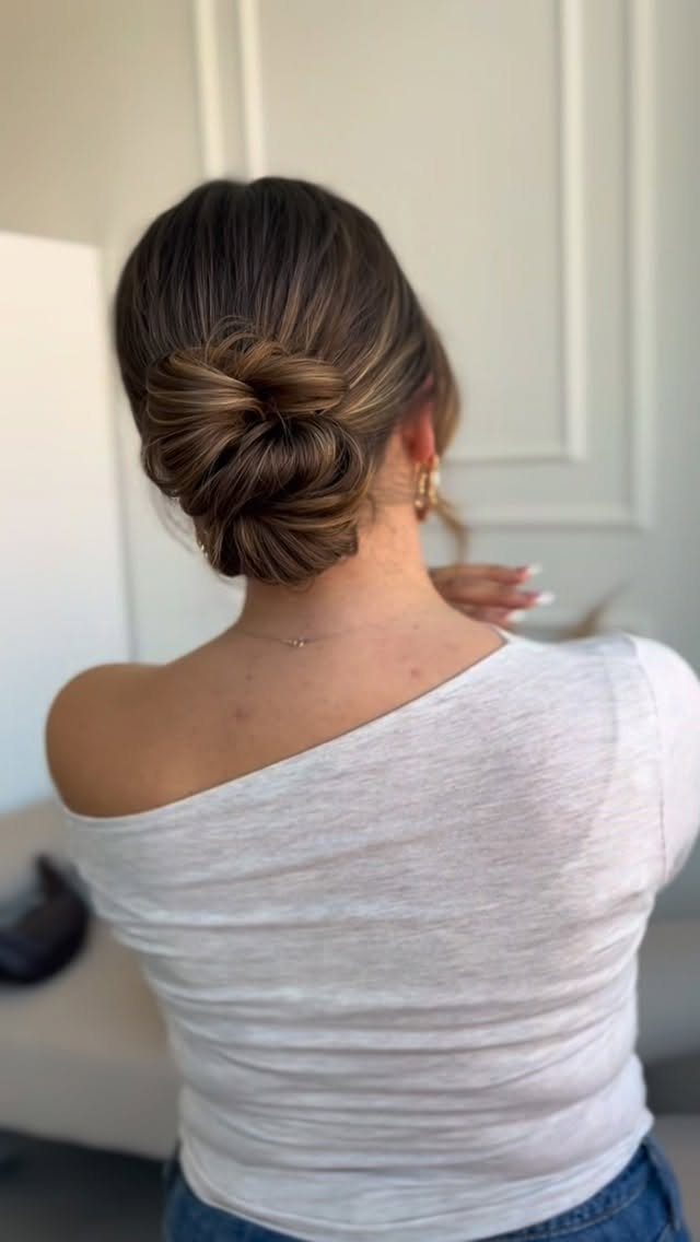 Woman with brown hair styled in a low twisted chignon bun from behind.