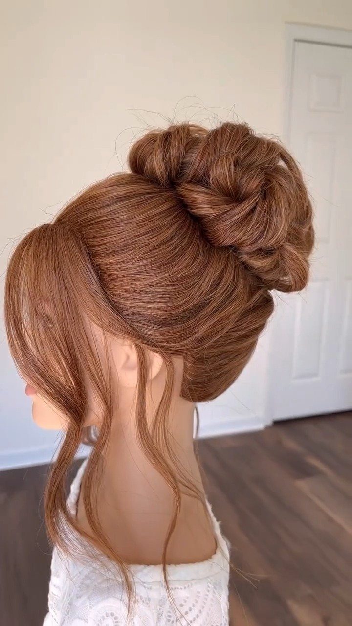 Reddish-brown hair styled in a high braided bun with loose face-framing tendrils.