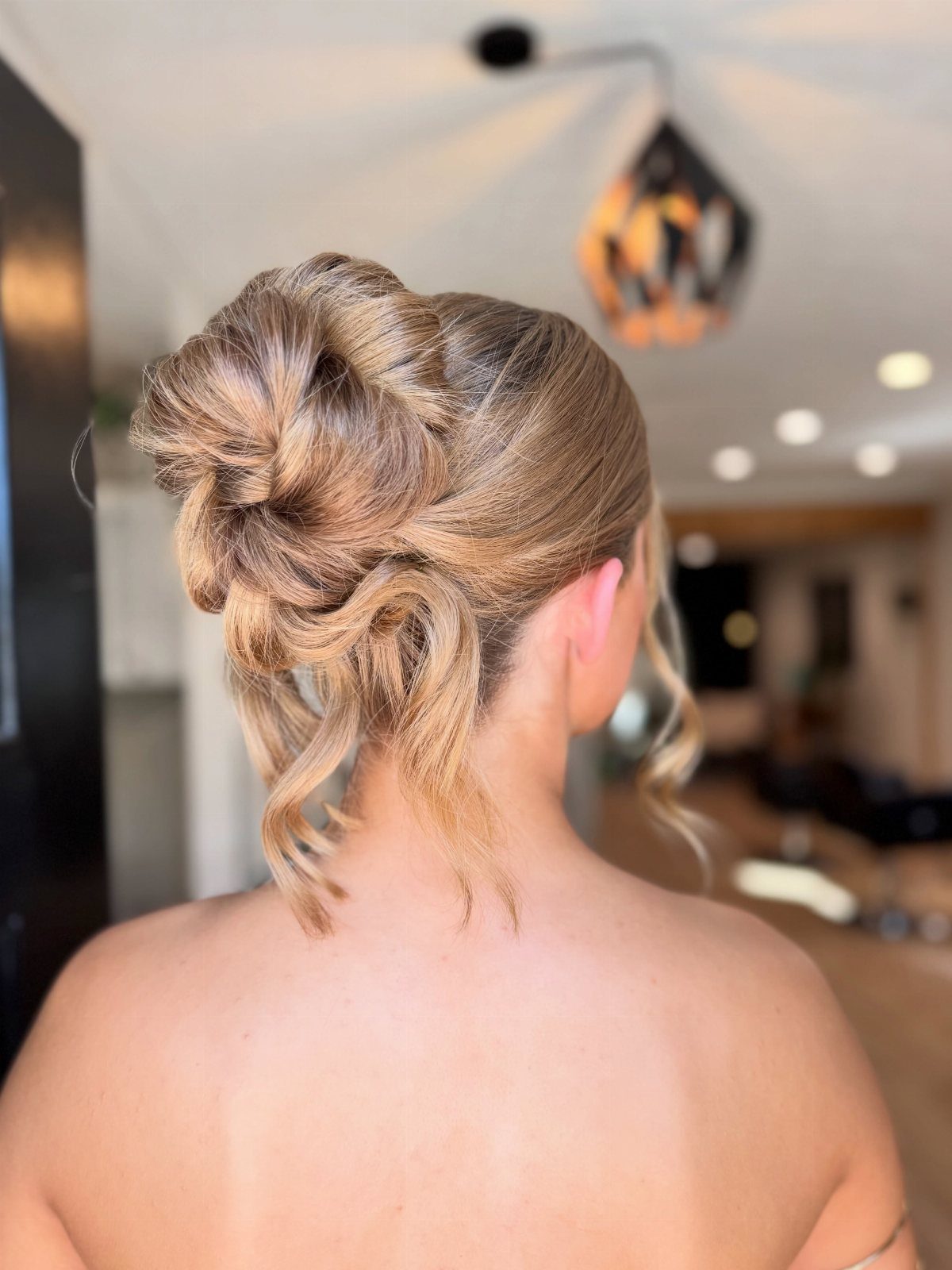 Blonde hair styled in a voluminous textured updo with loose curls and twists.