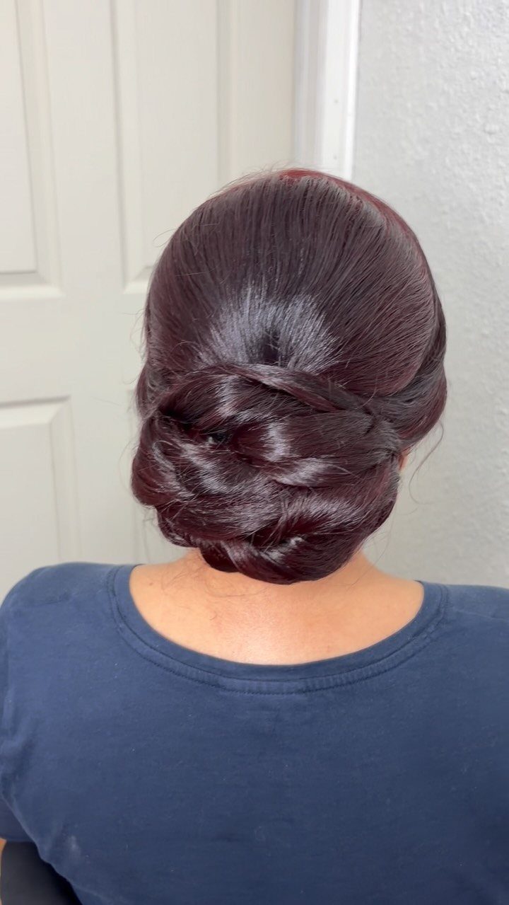 Dark burgundy hair styled into a polished, twisted chignon updo from behind.