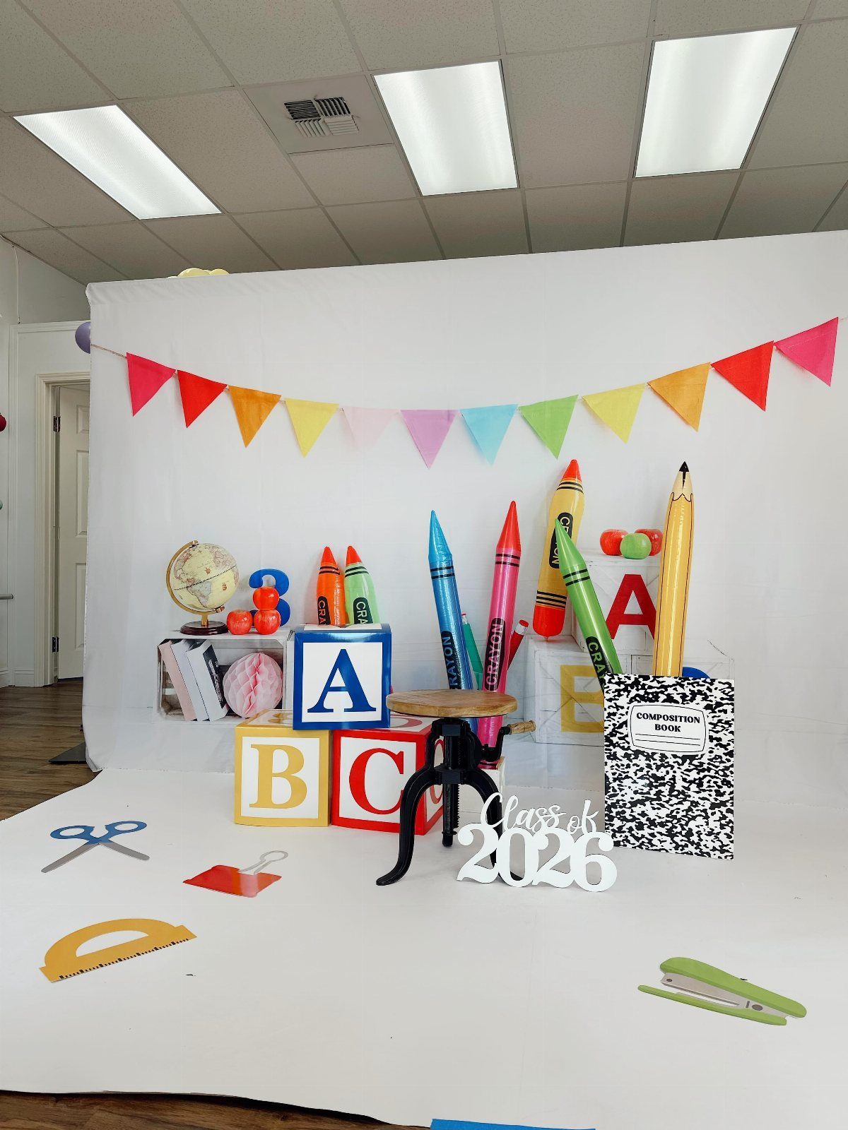 Graduation photo backdrop with giant crayons, alphabet blocks, and Class of 2026 sign.