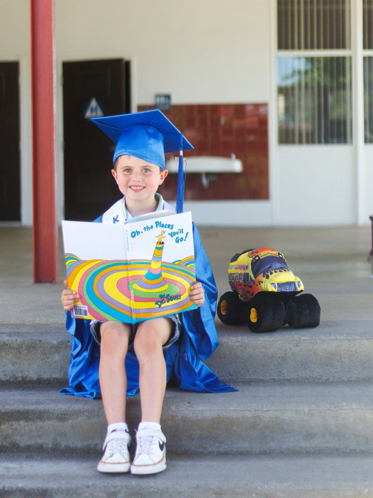 Young boy in blue graduation cap and gown holding a Dr. Seuss book