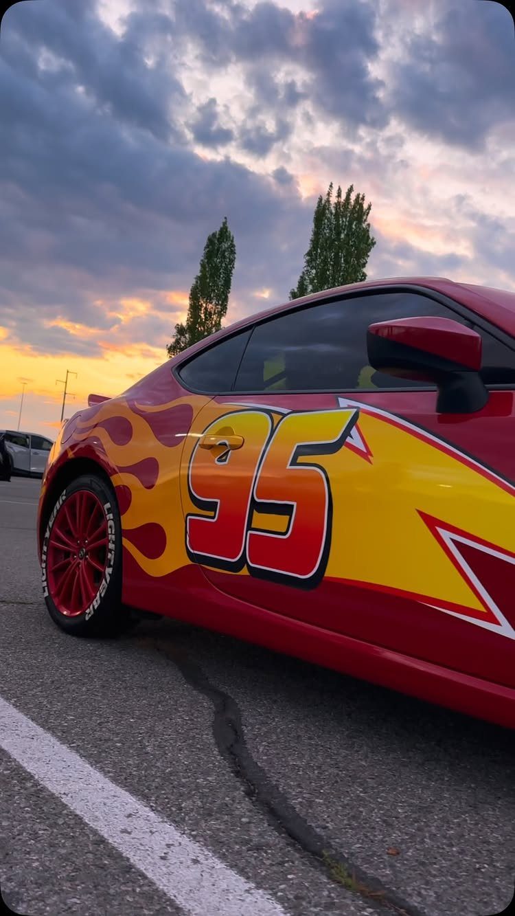 Red sports car with Lightning McQueen flame decals and number 95 at sunset