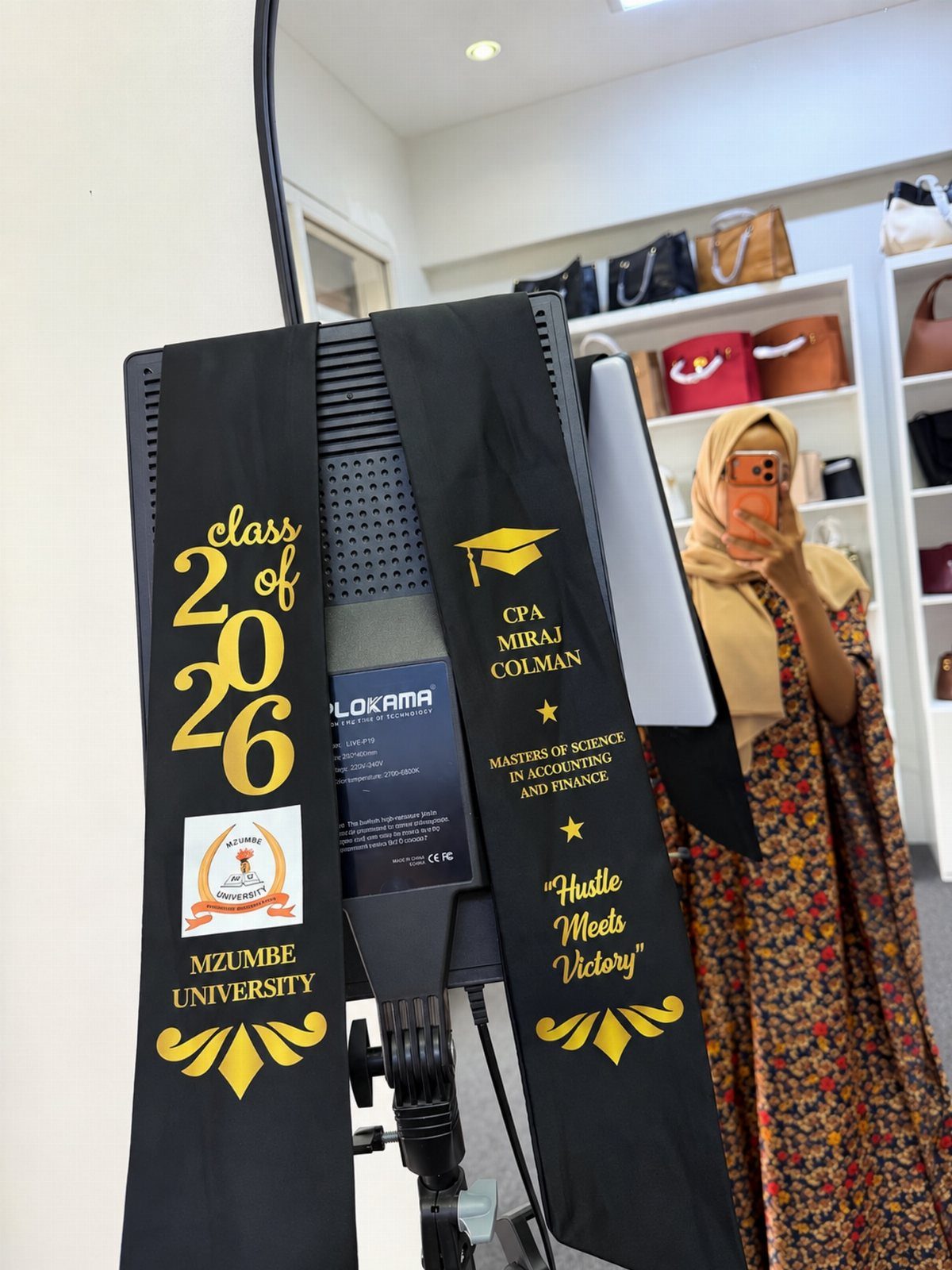 Black graduation stole with gold lettering and university logo draped over equipment.