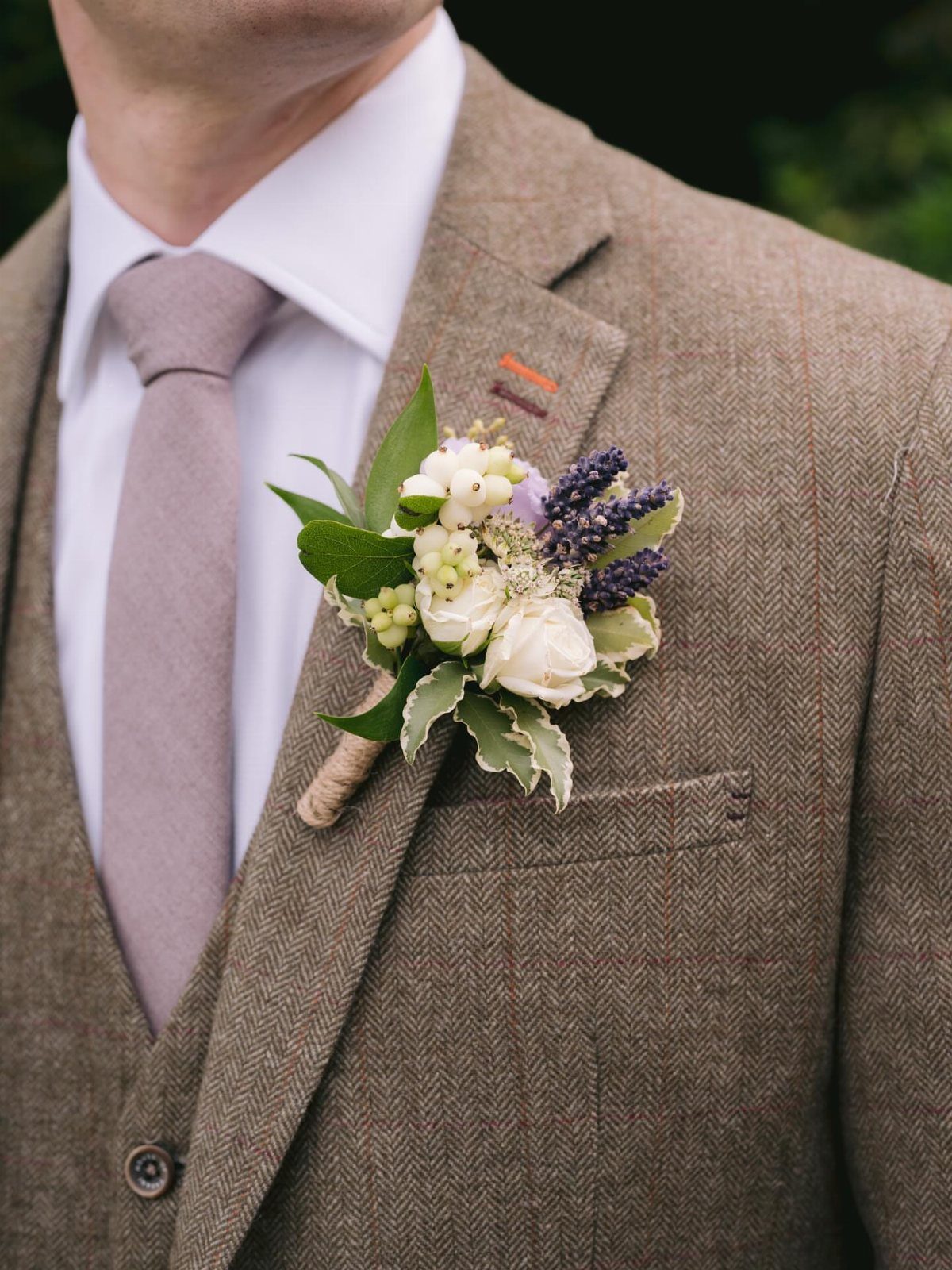 Man in brown tweed suit with mauve tie and floral lapel boutonniere