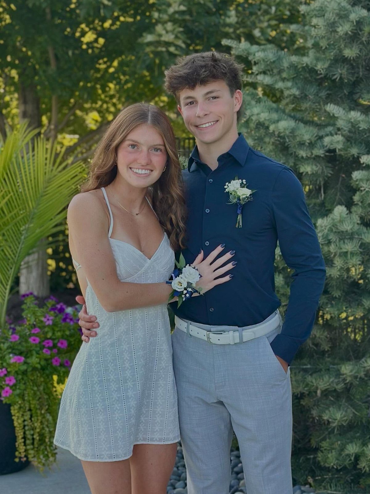 Teenage couple posing in semi-formal attire with a boutonniere and wrist corsage.