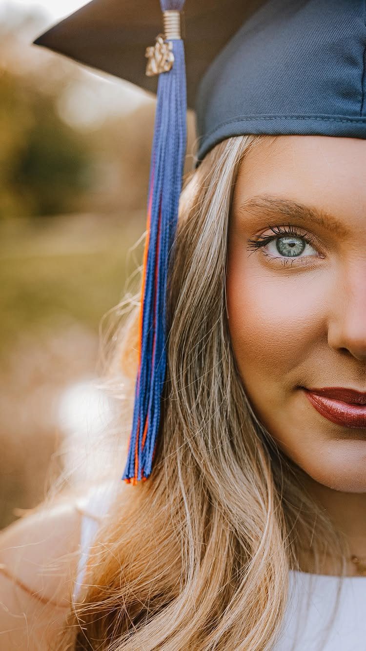 Young woman wearing a black graduation cap with a blue and orange tassel.