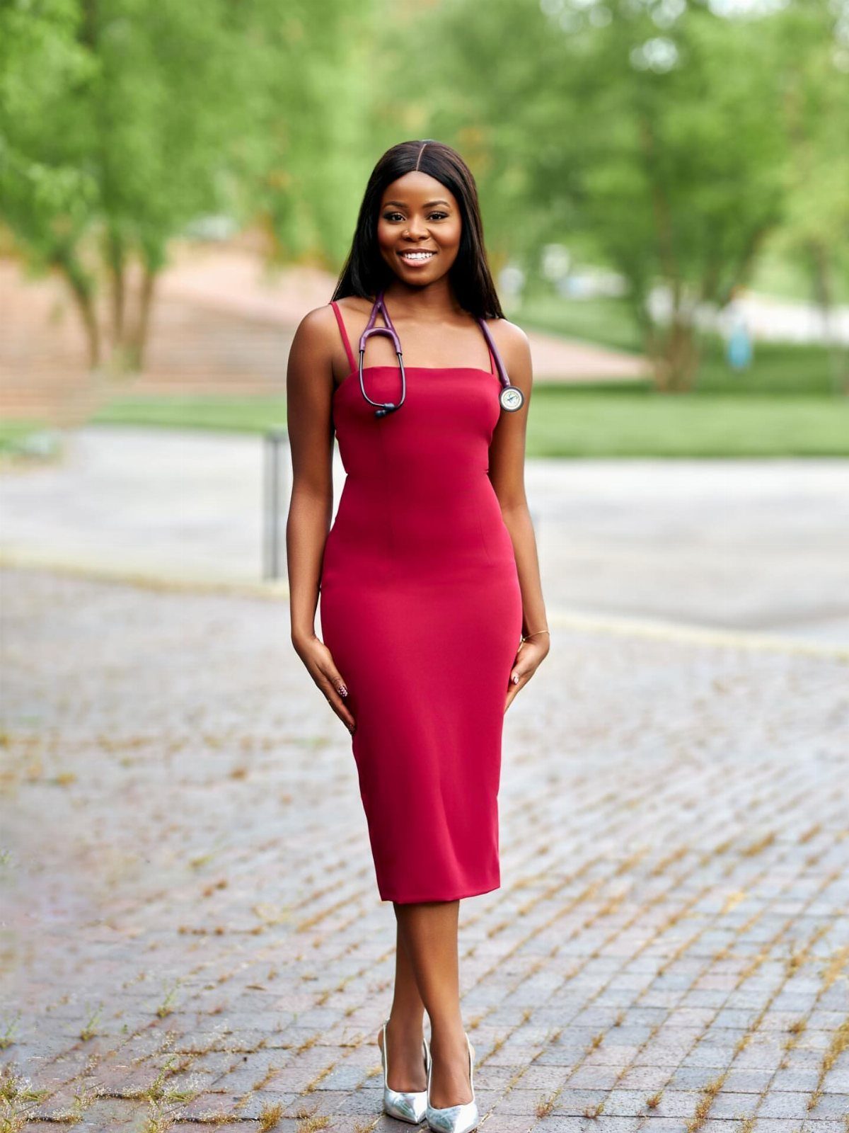 Woman in a red midi dress and silver heels with a stethoscope around her neck.