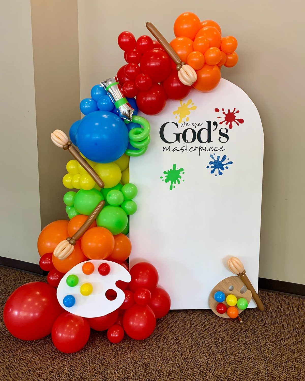 Colorful balloon arch and white backdrop with art theme for a graduation party