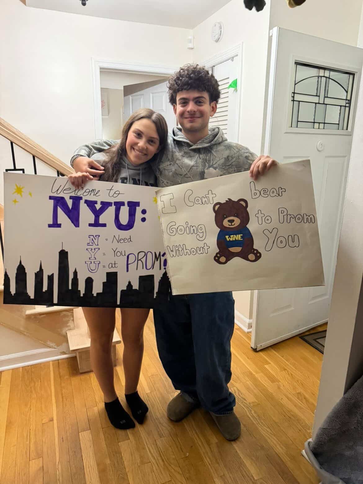 Teenage couple holding handmade promposal posters, one featuring a brown bear illustration.