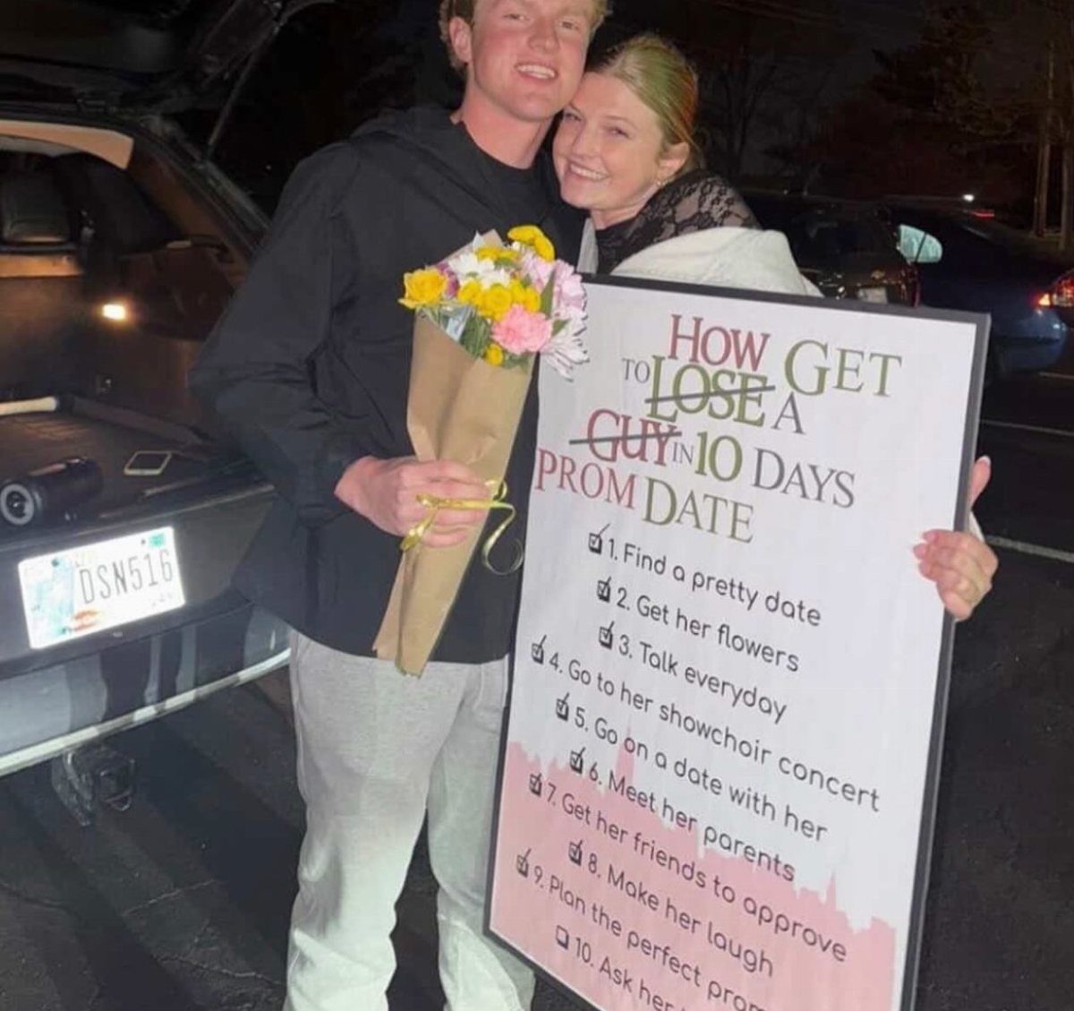 Young couple posing with a movie-themed promposal poster and a flower bouquet.