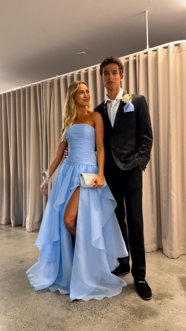 Young couple posing in formal prom attire with a light blue gown.
