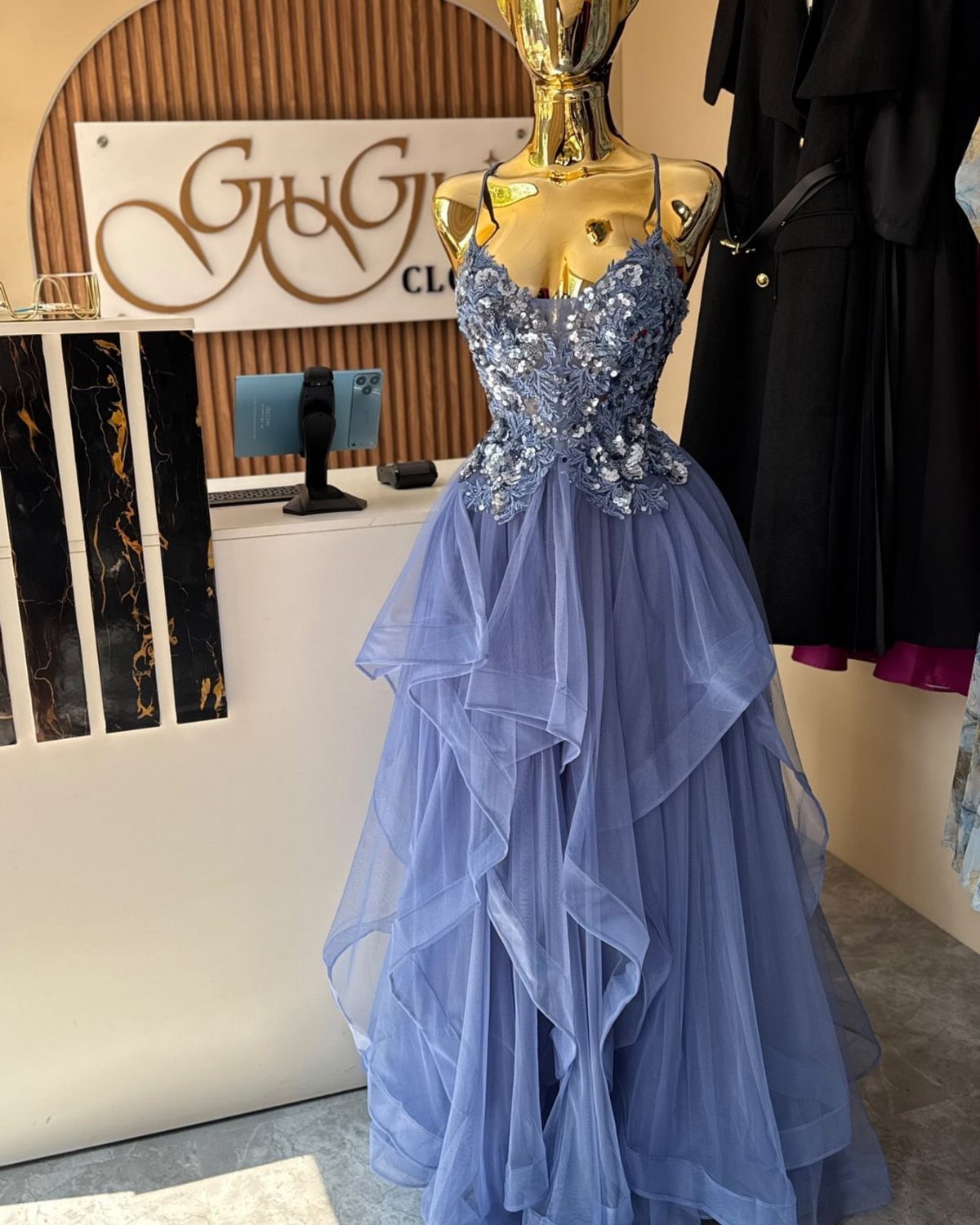 Periwinkle blue prom dress with beaded bodice on a gold mannequin in store