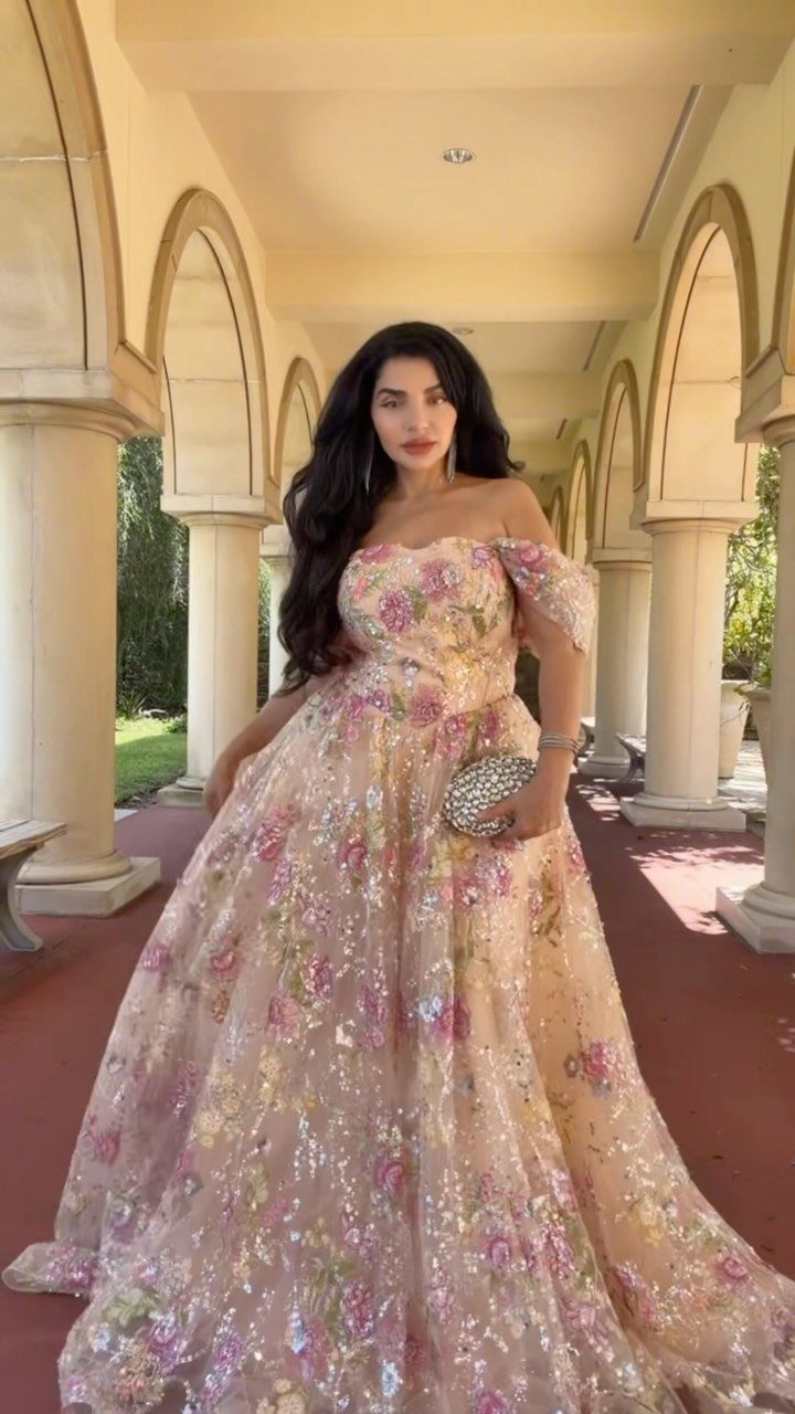 Woman in a floor-length floral embroidered sequin gown standing in a colonnade
