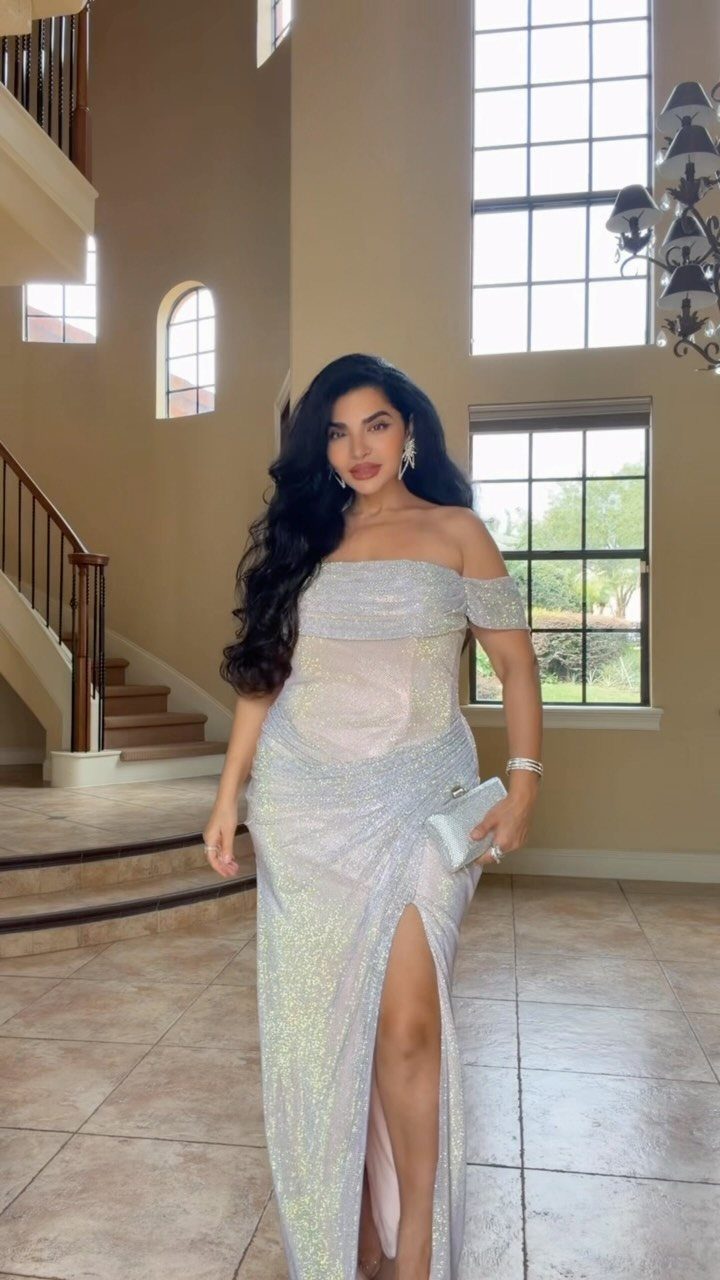 Woman in a shimmering silver off-the-shoulder gown with a high leg slit.