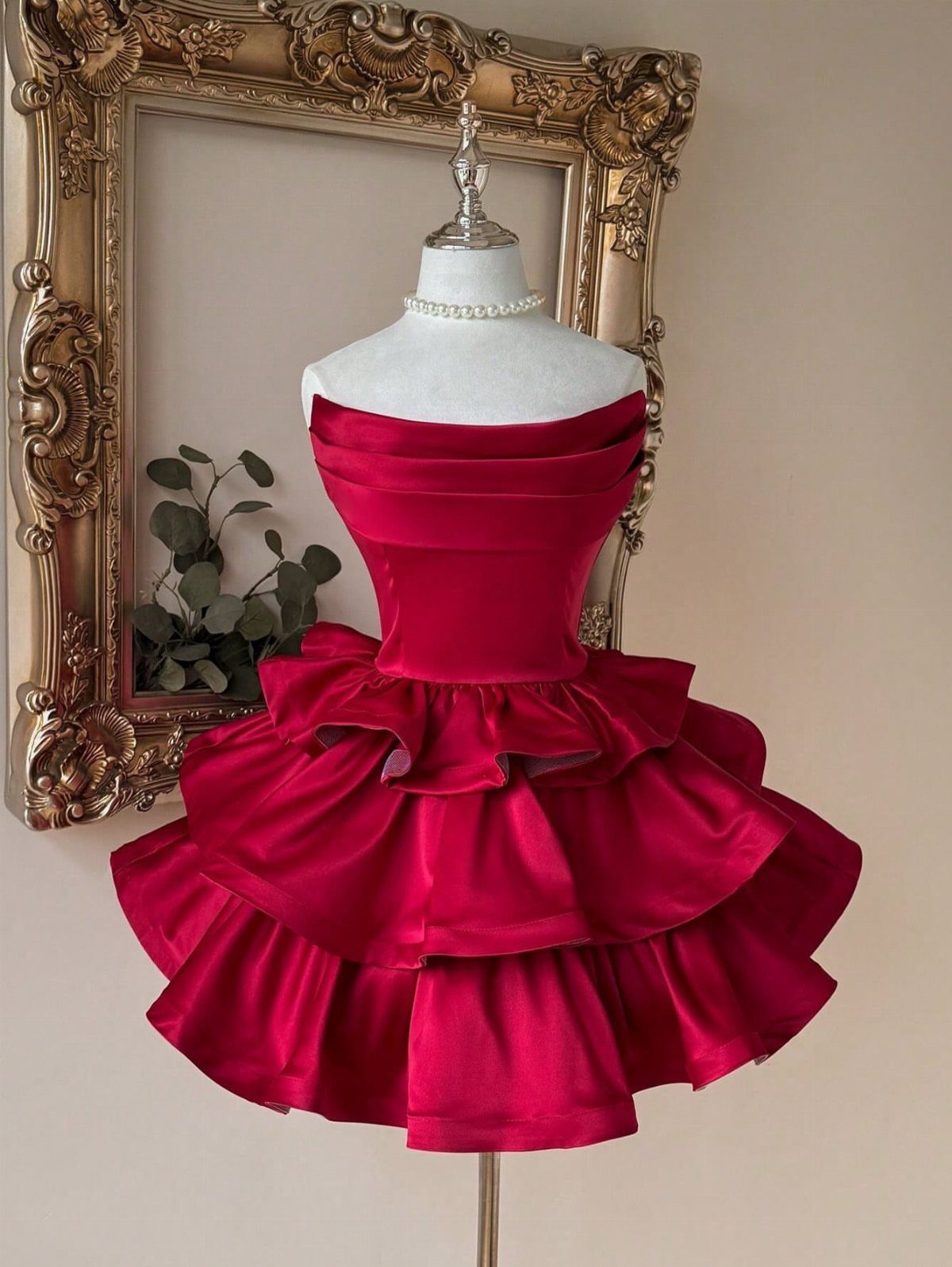 Red satin strapless mini dress with tiered ruffles on a white mannequin.