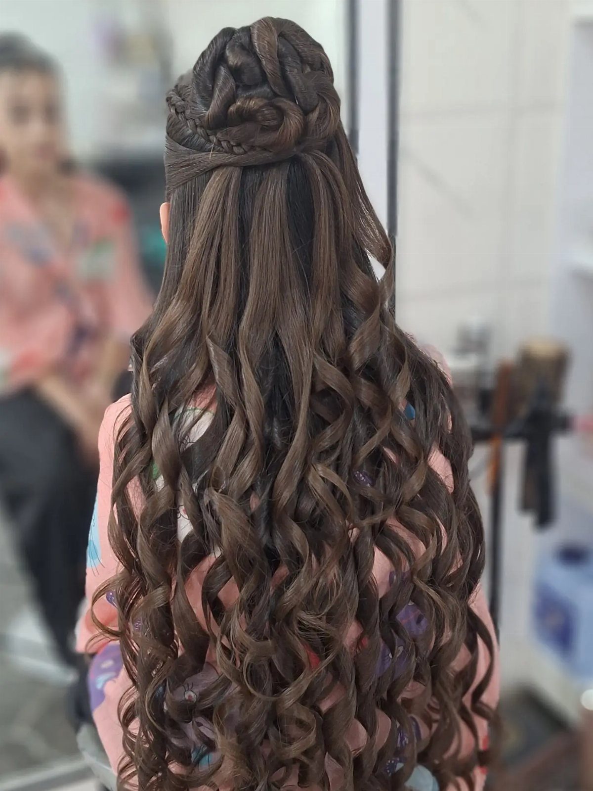 Brown hair styled in a half-up bun with long loose curls below