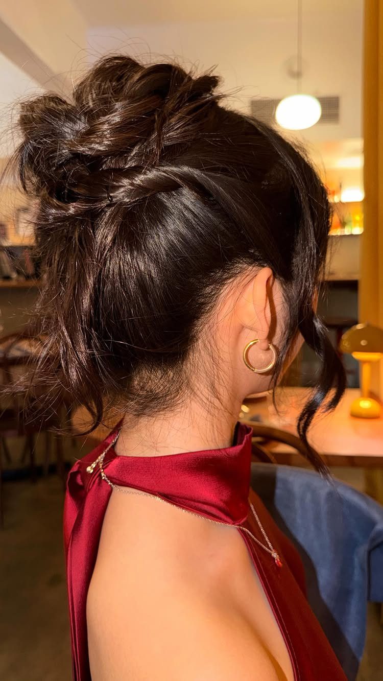 Woman with dark brown hair in a textured high bun wearing red satin.