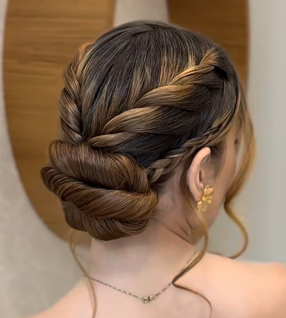 Woman's brown hair styled in a braided updo with a low coiled bun.