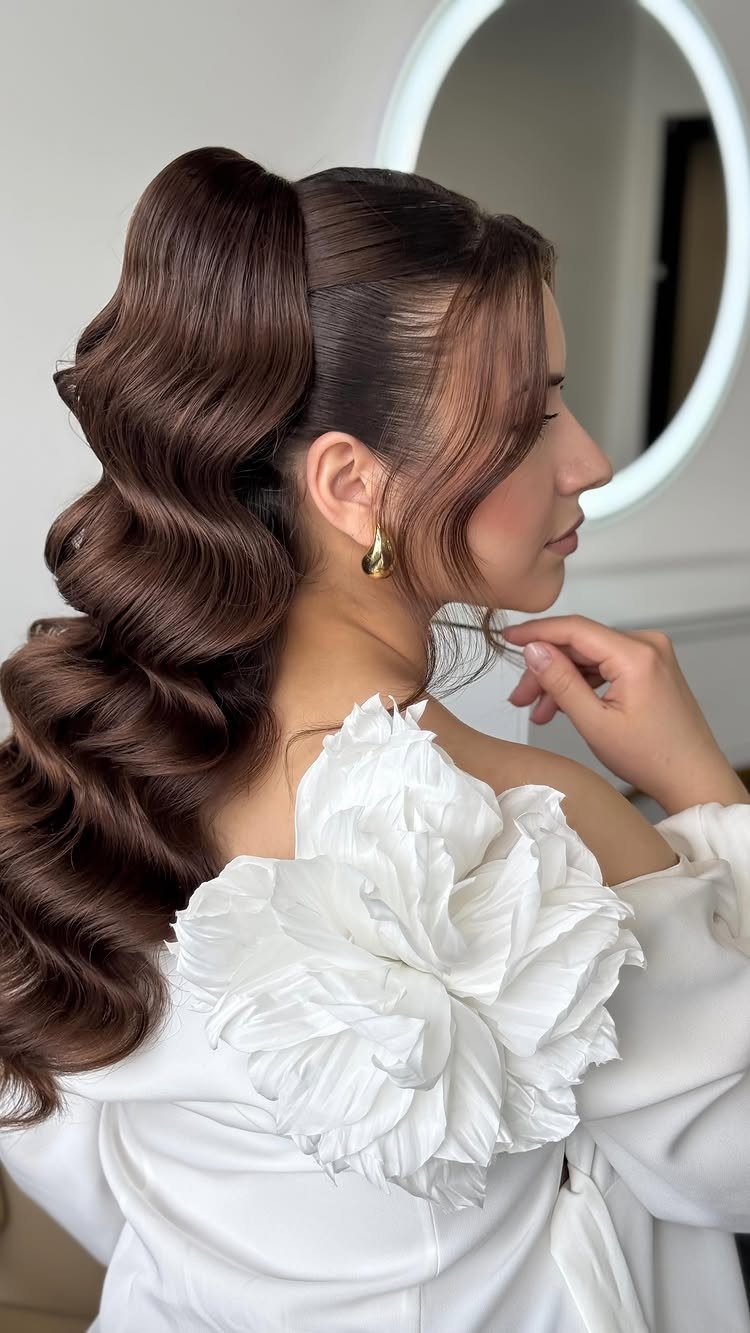 Woman with a voluminous high ponytail featuring structured brown waves and white floral dress.