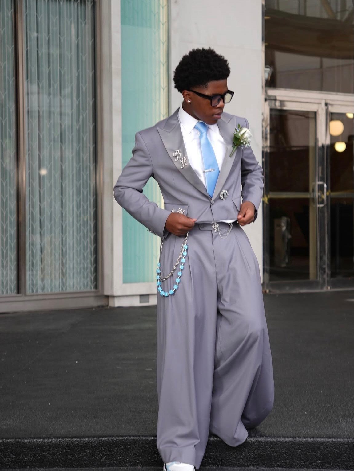Young man in a grey suit with wide-leg pants and light blue tie.