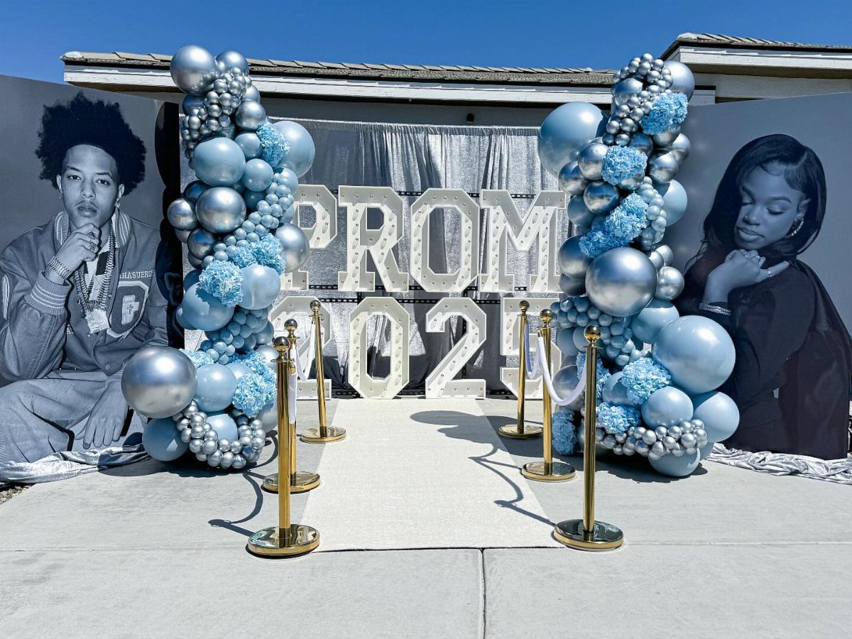 Prom photo backdrop with blue and silver balloon arches and large silver lettering.
