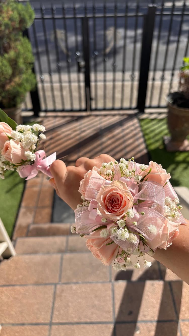Pink rose corsage on a wrist and a matching boutonnière held nearby.