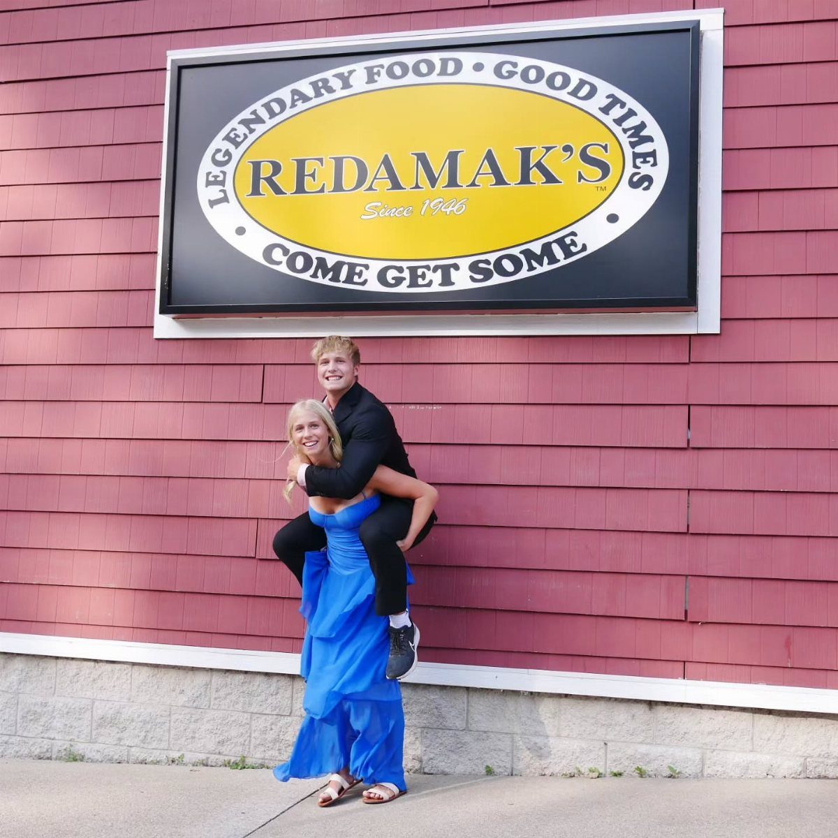 Young couple in formal prom attire posing for a piggyback ride outdoors.