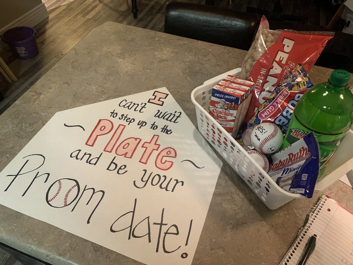 Baseball themed prom proposal poster next to a basket of snacks and drinks.