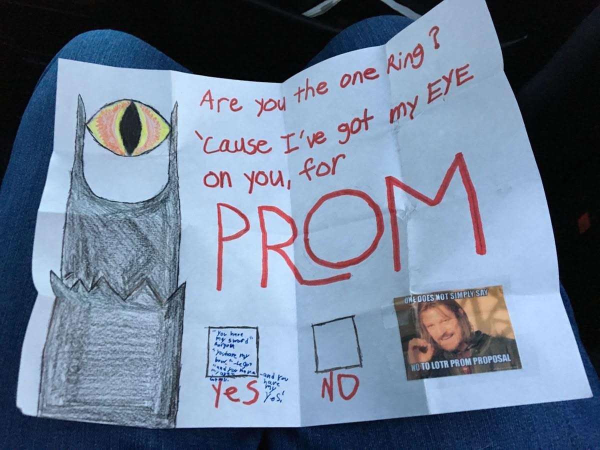 Hand-drawn Lord of the Rings themed prom proposal poster resting on blue jeans.