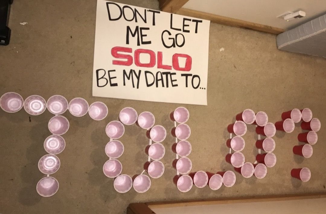Prom proposal poster and red solo cups spelling out SOLO on a floor