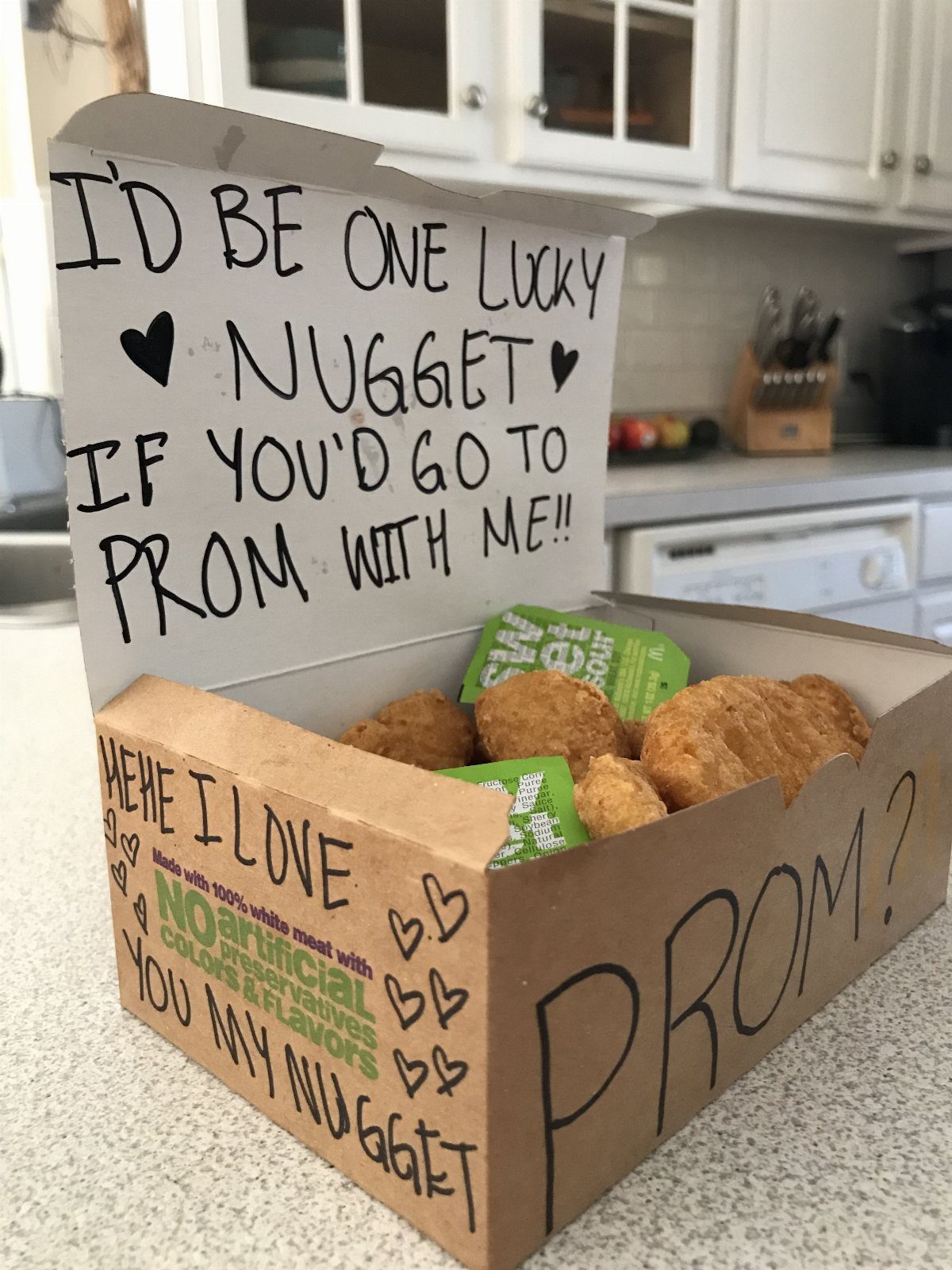 Cardboard chicken nugget box with handwritten promposal message and fried chicken nuggets inside.