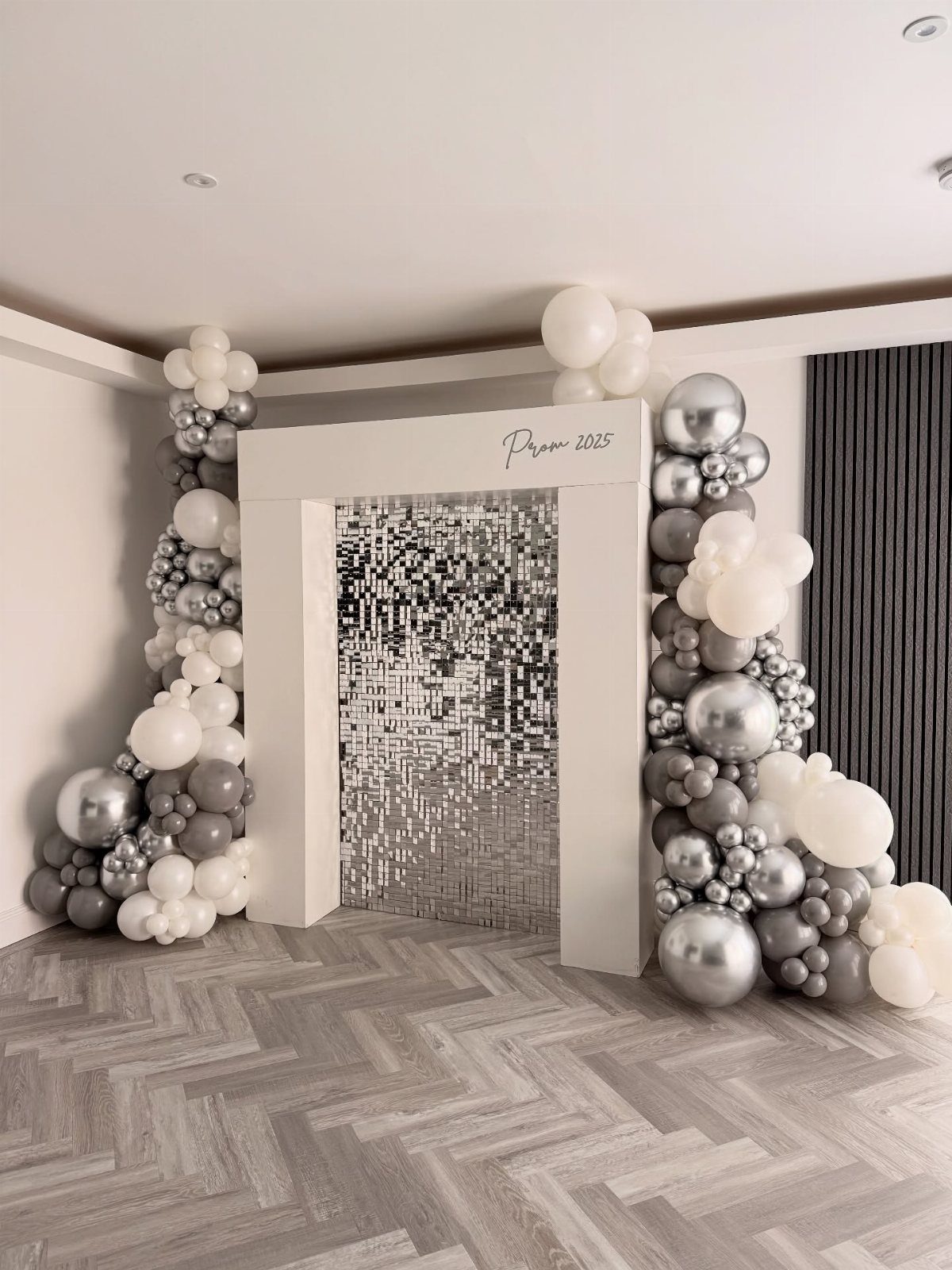 White frame backdrop with silver sequin curtain and white and grey balloons